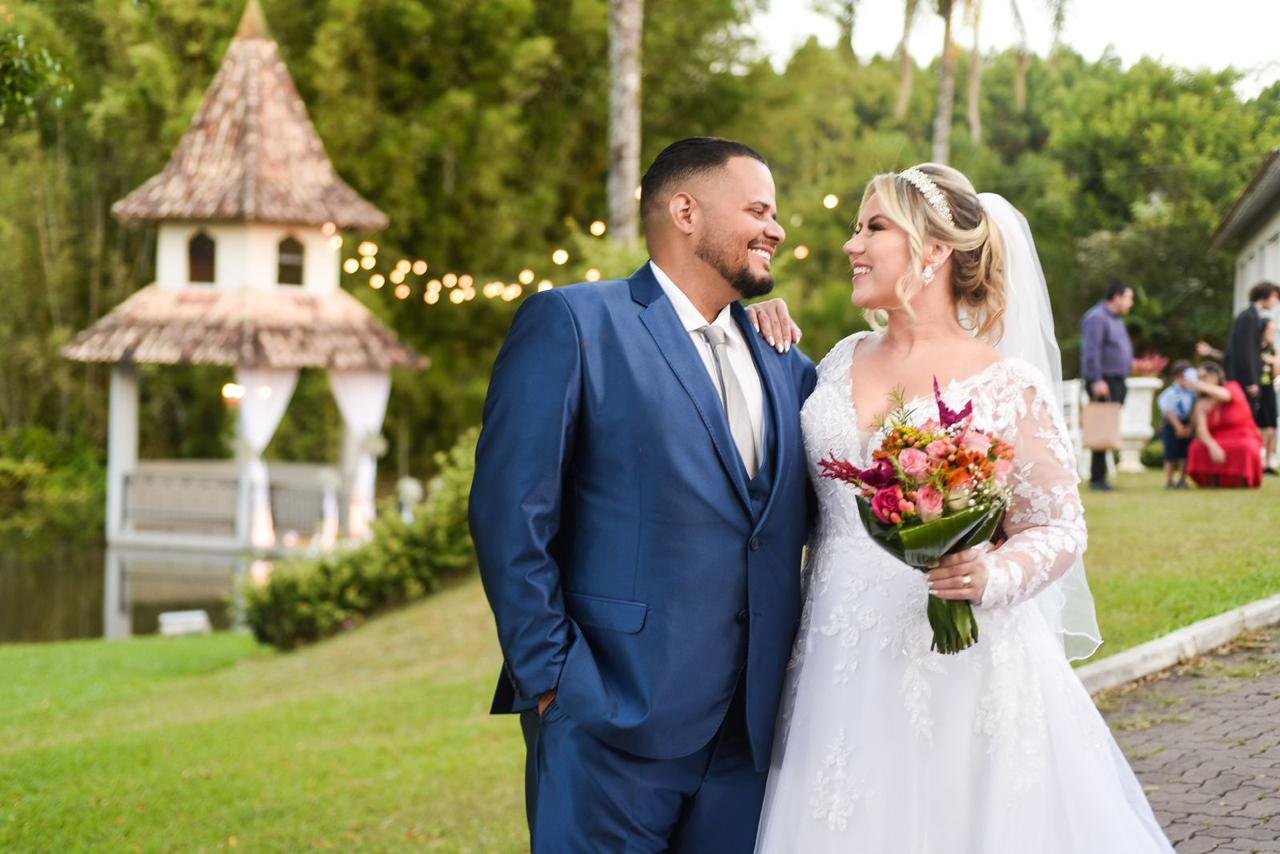 Casal de noivos sorrindo no jardim, em luz natural